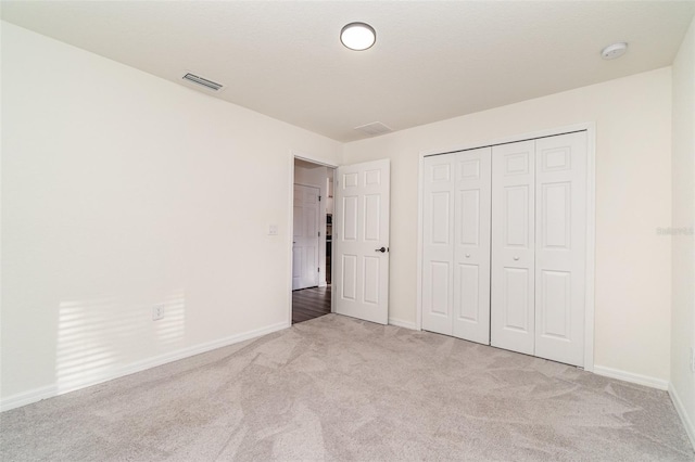 unfurnished bedroom featuring carpet, a closet, visible vents, and baseboards