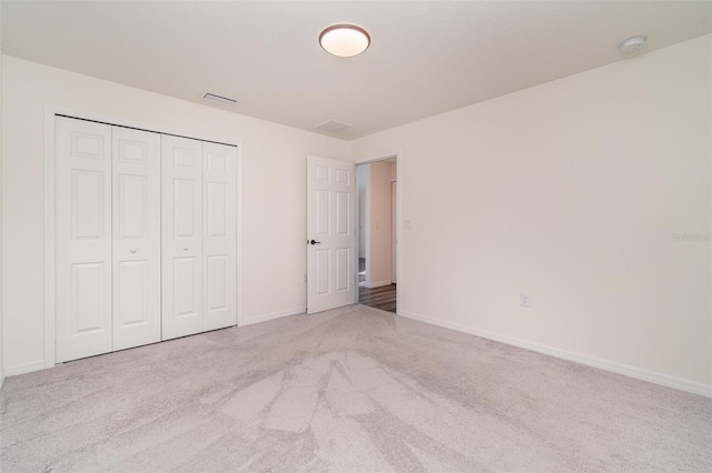 unfurnished bedroom featuring carpet, a closet, visible vents, and baseboards