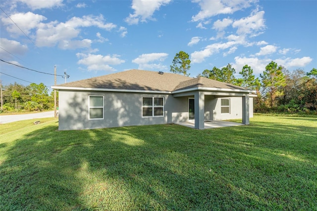 rear view of house with a patio, a yard, roof with shingles, and stucco siding