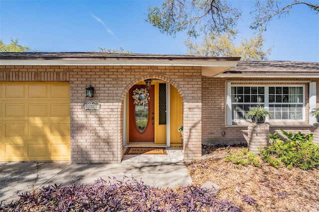 entrance to property with a garage and brick siding