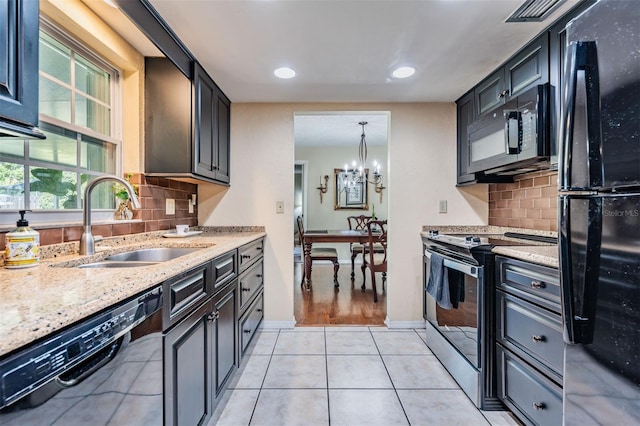 kitchen with light tile patterned flooring, a notable chandelier, a sink, light stone countertops, and black appliances