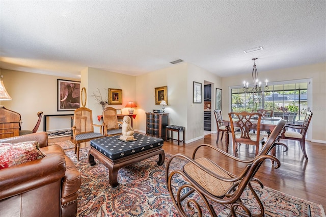 living area featuring a chandelier, visible vents, baseboards, and wood finished floors