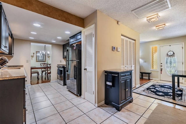 kitchen with light tile patterned floors, stainless steel stove, a sink, visible vents, and freestanding refrigerator