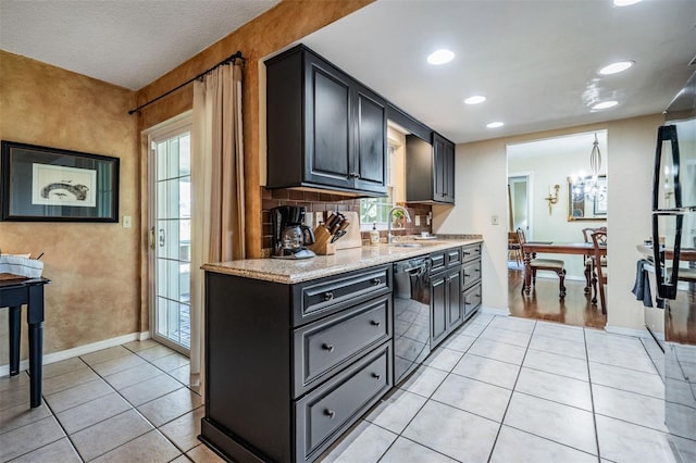 kitchen with light tile patterned floors, baseboards, dishwasher, backsplash, and a sink