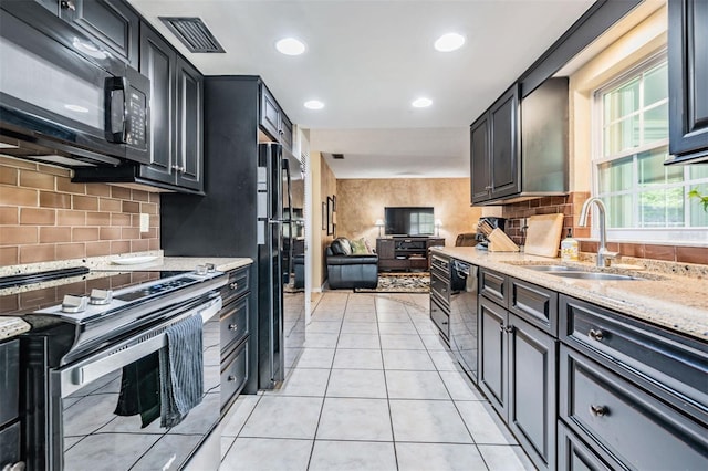 kitchen featuring light tile patterned floors, light stone counters, a sink, visible vents, and black appliances