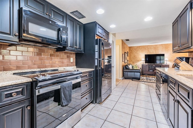 kitchen with light stone counters, light tile patterned floors, visible vents, open floor plan, and black appliances