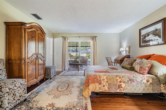 bedroom with access to outside, a textured ceiling, visible vents, and wood finished floors