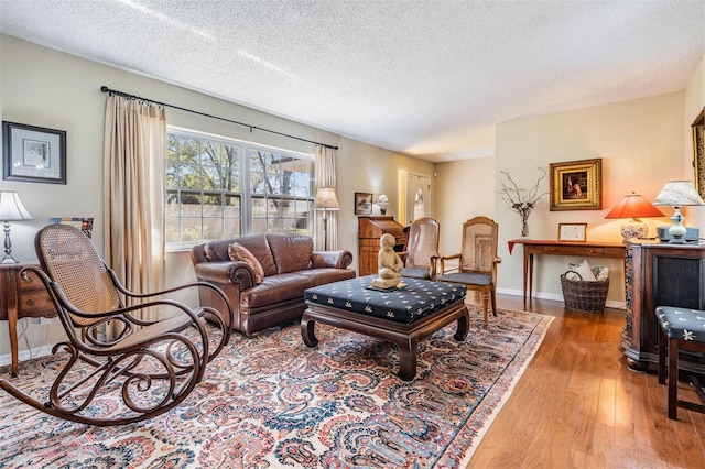 living room featuring a textured ceiling, wood finished floors, and baseboards