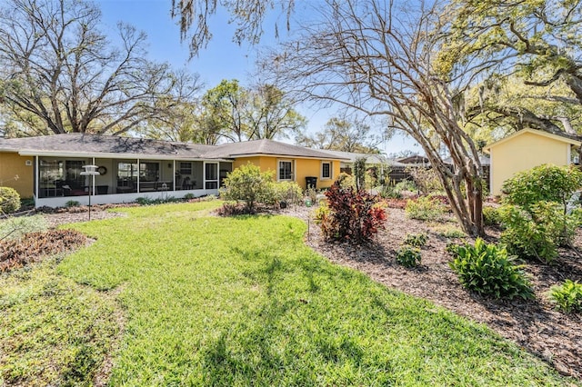 rear view of property featuring a sunroom, a lawn, and stucco siding