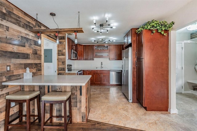 kitchen featuring stainless steel appliances, wood walls, a peninsula, and a breakfast bar area