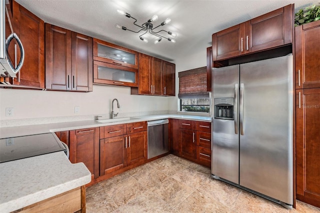 kitchen with glass insert cabinets, stainless steel appliances, a sink, and light countertops