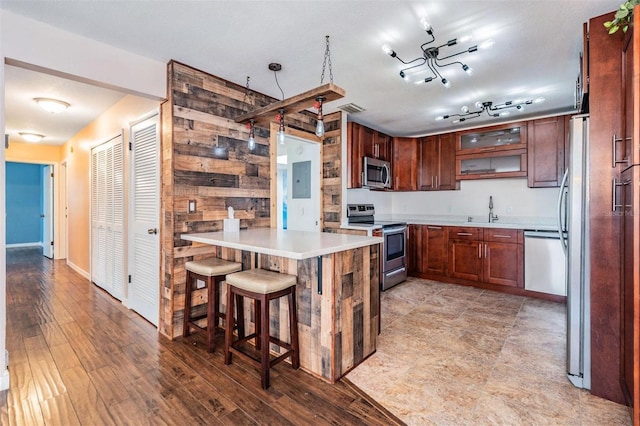 kitchen with a peninsula, light wood-style floors, light countertops, appliances with stainless steel finishes, and a kitchen bar