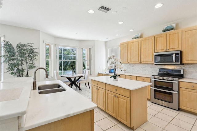 kitchen featuring a center island, visible vents, appliances with stainless steel finishes, light brown cabinets, and a sink