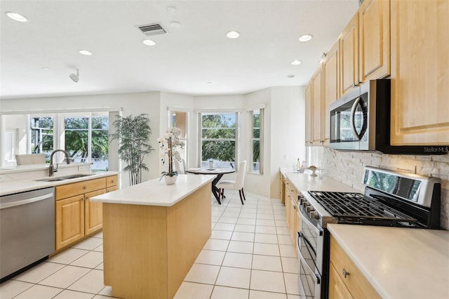 kitchen featuring appliances with stainless steel finishes, light brown cabinets, a sink, and visible vents