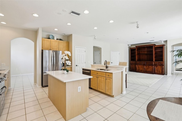 kitchen featuring visible vents, arched walkways, a kitchen island with sink, stainless steel appliances, and a sink