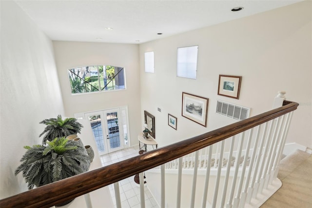 staircase featuring a towering ceiling, tile patterned flooring, recessed lighting, and french doors