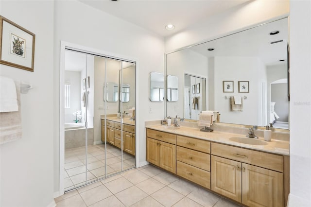 bathroom with double vanity, a bathing tub, a sink, and tile patterned floors
