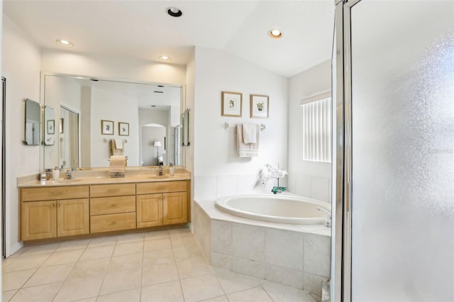 bathroom with double vanity, a bath, lofted ceiling, tile patterned flooring, and a sink