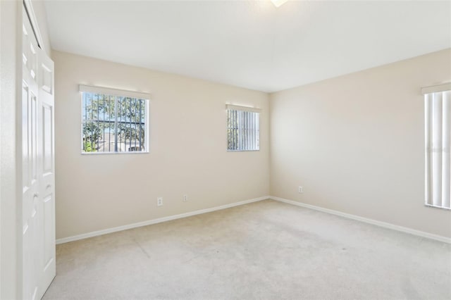 unfurnished bedroom with baseboards, a closet, and light colored carpet