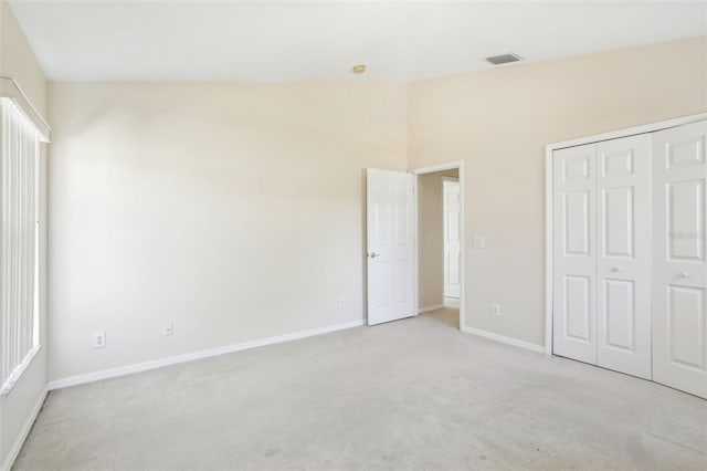 unfurnished bedroom with light carpet, a closet, visible vents, and baseboards
