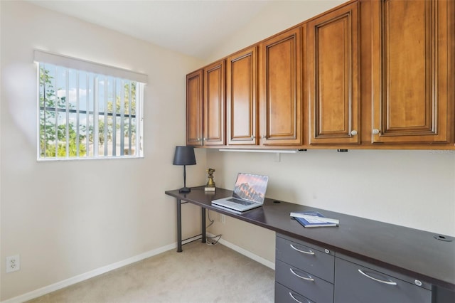 unfurnished office featuring baseboards, light colored carpet, and built in study area
