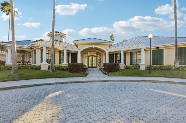 exterior space featuring french doors, stucco siding, a standing seam roof, metal roof, and a front lawn
