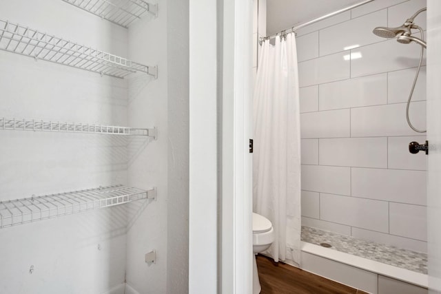 bathroom featuring a stall shower, wood finished floors, and toilet