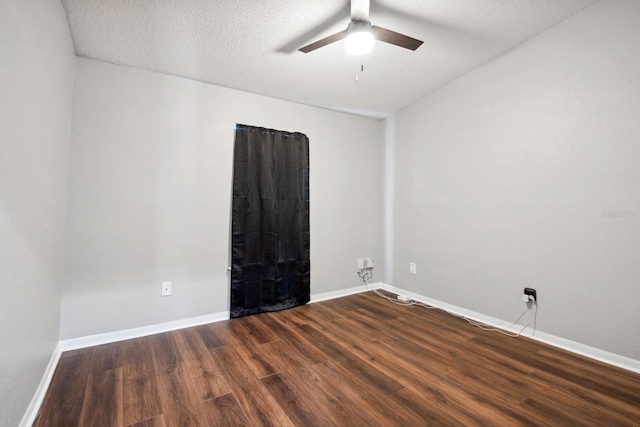 empty room with a ceiling fan, dark wood finished floors, a textured ceiling, and baseboards