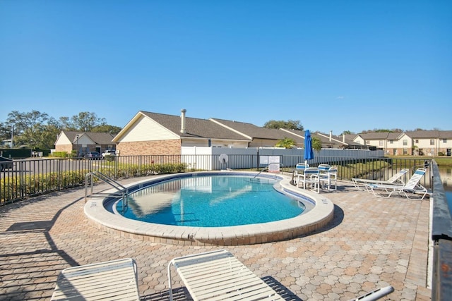 community pool with a patio area, a residential view, and fence