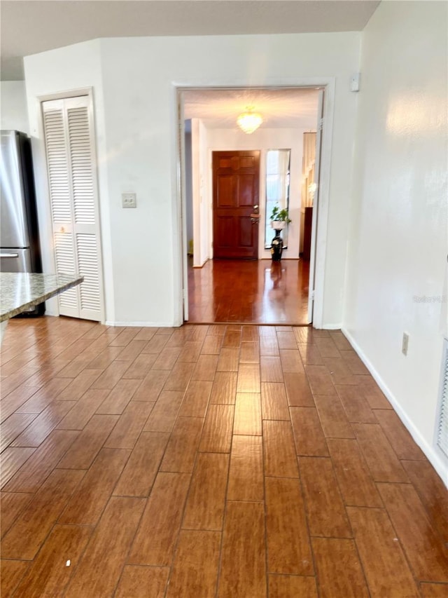 corridor featuring baseboards and wood finished floors