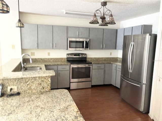 kitchen featuring appliances with stainless steel finishes, dark wood-style flooring, a sink, and gray cabinetry