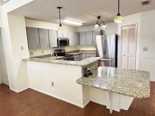 kitchen featuring appliances with stainless steel finishes, visible vents, dark wood finished floors, and a peninsula