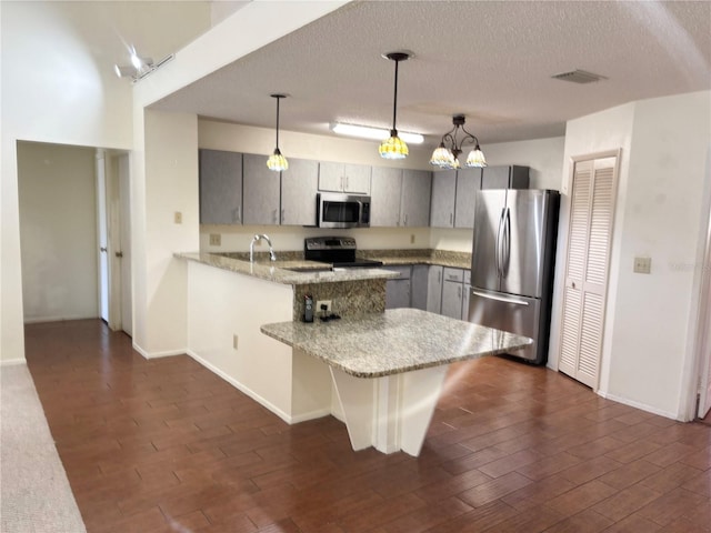 kitchen featuring stainless steel appliances, visible vents, dark wood-type flooring, and a peninsula