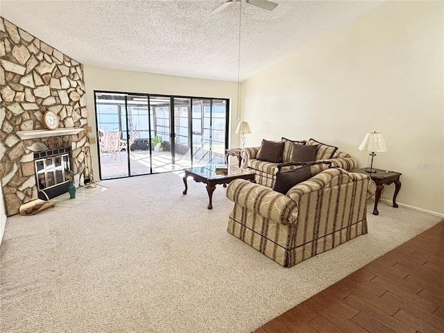 living area featuring a textured ceiling, ceiling fan, a fireplace, and wood finished floors