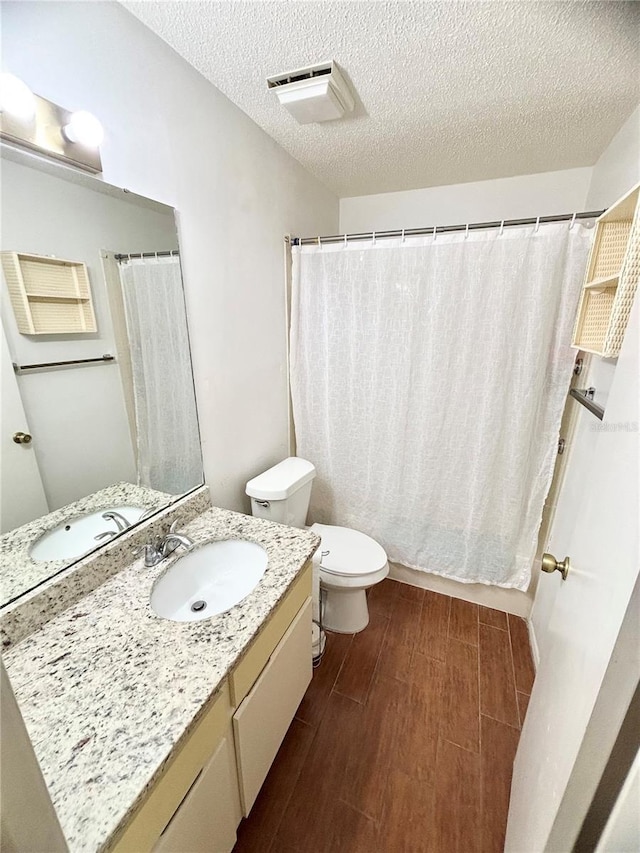 full bathroom with wood tiled floor, vanity, toilet, and a textured ceiling