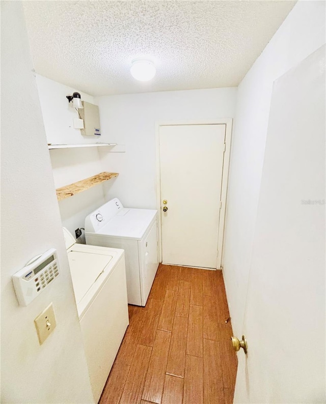 laundry area featuring a textured ceiling, laundry area, light wood-style flooring, and washer and dryer