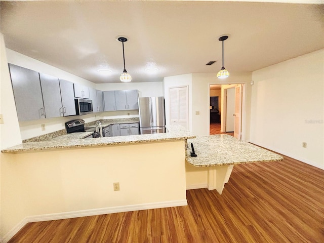 15013 Redcliff Dr, Tampa, FL 33625 - kitchen featuring stainless steel appliances, wood finished floors, baseboards, and a peninsula