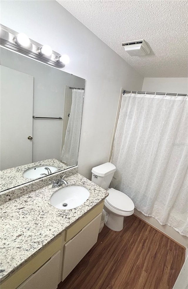 15013 Redcliff Dr, Tampa, FL 33625 - bathroom with wood finished floors, a textured ceiling, vanity, toilet, and a shower with shower curtain