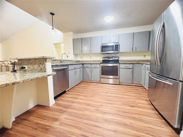 15013 Redcliff Dr, Tampa, FL 33625 - kitchen featuring appliances with stainless steel finishes, gray cabinets, light wood finished floors, a peninsula, and a textured ceiling