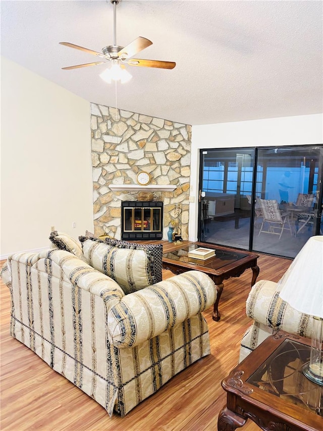 15013 Redcliff Dr, Tampa, FL 33625 - living room with a ceiling fan, wood finished floors, a stone fireplace, and a textured ceiling