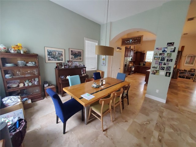 dining room featuring arched walkways, visible vents, and baseboards