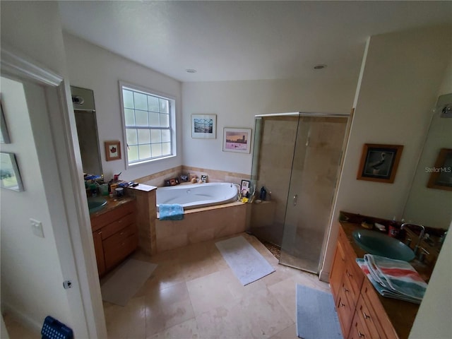 bathroom featuring a stall shower, two vanities, a sink, and a bath