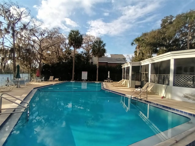 community pool featuring a sunroom and a patio area