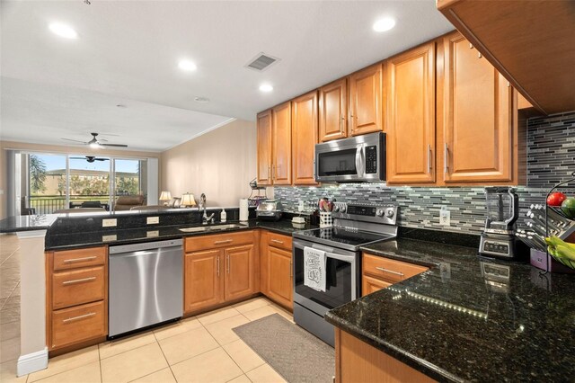 kitchen featuring stainless steel appliances, a peninsula, a sink, visible vents, and decorative backsplash