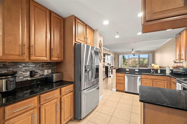 kitchen with light tile patterned floors, stainless steel appliances, backsplash, brown cabinetry, and a sink