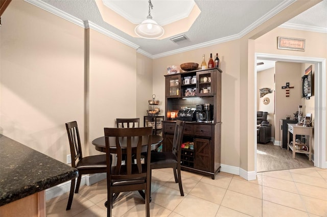 dining room with baseboards, visible vents, a raised ceiling, ornamental molding, and light tile patterned flooring