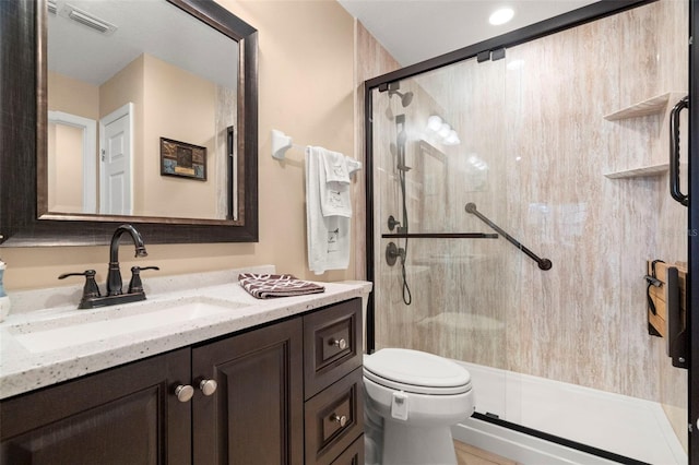 bathroom with toilet, a stall shower, vanity, and visible vents