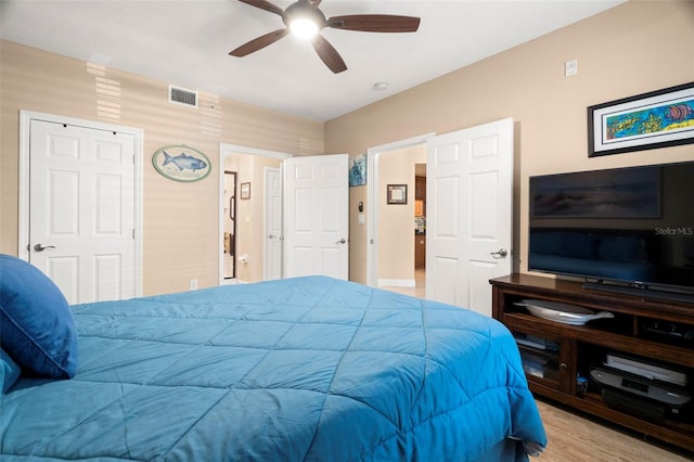 bedroom with a ceiling fan, visible vents, and wood finished floors