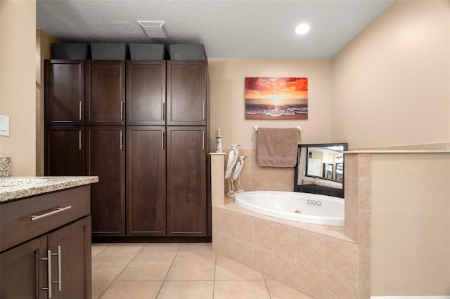 full bath featuring a textured ceiling, vanity, visible vents, a jetted tub, and tile patterned floors