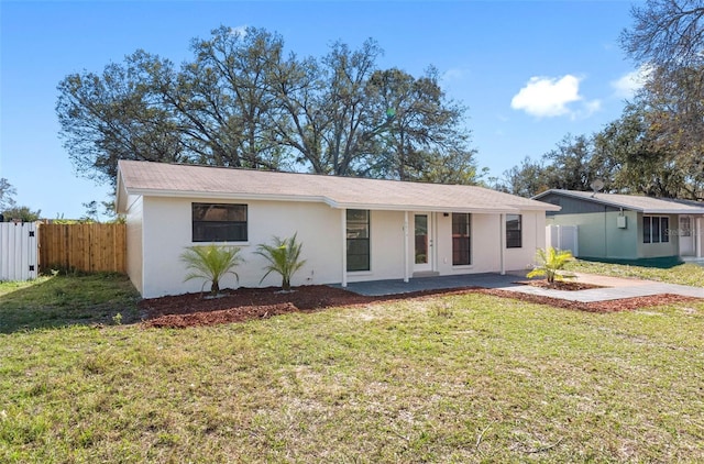 ranch-style home featuring a front lawn, fence, and stucco siding